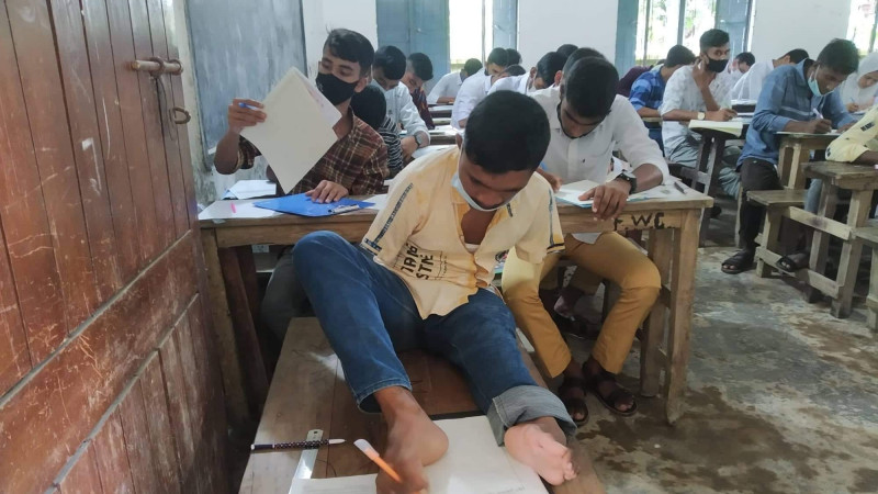 ফুলবাড়িতে,জন্মপ্রতিবন্ধী মানিক মিয়া পা দিয়ে দিচ্ছেন এসএসসি পরীক্ষা